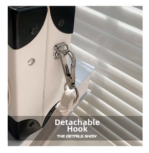 Detail of white textured leather radio bag with silver lobster clasp and black corner