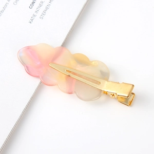 Macro detail of wave-shaped hair clip showing gradient resin texture and gold metal base