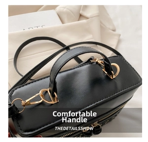 Detail of the black leather handbag's golden hardware and comfortable carry handle