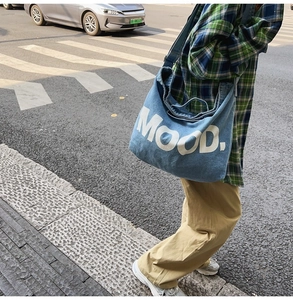 Blue denim tote bag with MOOD lettering shown in a stylish street style commute setting