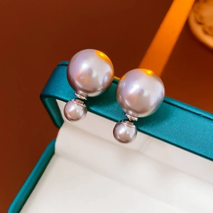 Macro shot of metallic lavender pearl double-stud earrings on a silk jewelry box