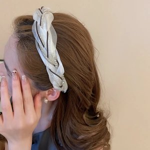 Close-up of woven mesh headband featuring white pearls and elegant fabric texture