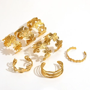 Golden titanium steel open bangles set with floral and butterfly charms on white background