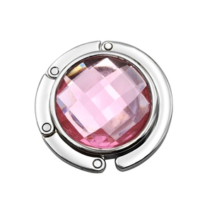 Detail of pink crystal folding handbag hook with silver metal polished casing for table