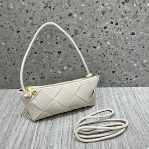 Detail shot of cream woven leather shoulder bag with gold zipper and textured surface