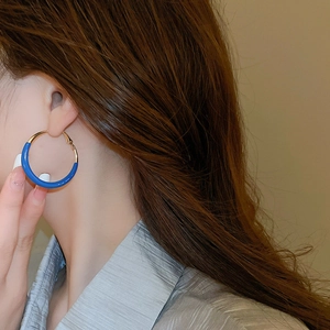 Close-up of elegant klein blue and gold circular earrings worn by a female model