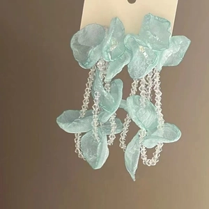 Détail de boucles d'oreilles fleurs bleues avec de longues franges en perles