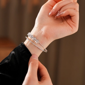 Détail d'un bracelet fleur à double couche argenté avec des zircons sur un poignet féminin
