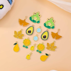 Macro shot of colorful enamel alloy charms featuring frog, avocado, and sunflower motifs