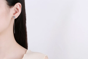 Detail view of a long silver ear threader with a snowflake-shaped moissanite floral stud