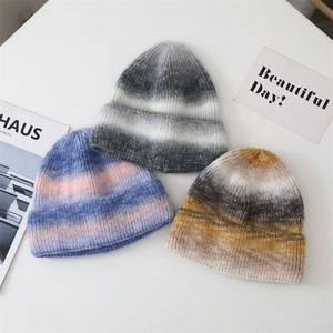 Close-up of tie-dye knit beanies showing gradient texture in blue, pink, and grey