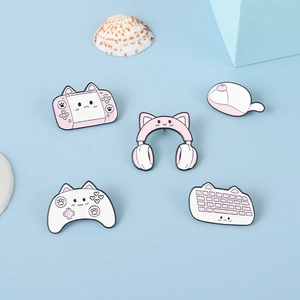 Detailed close-up of pink cat-ear enamel pins set with gaming console and keyboard