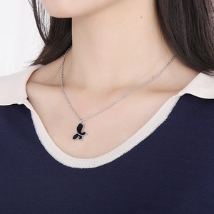Silver stainless steel necklace featuring asymmetrical black butterfly pendant on model