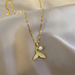 Detailed close-up of golden mermaid tail necklace with pavé zircon and pearl on grey silk