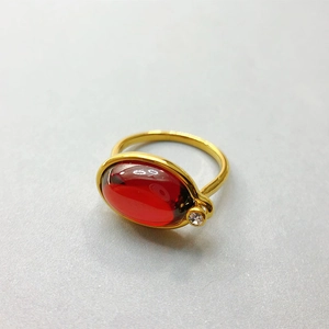 Detail eines 18K vergoldeten Rings mit ovalem rotem Edelstein und klarem Zirkonia-Akzent