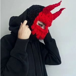 Detailed close-up of handmade crochet balaclava with red devil horns and knit texture