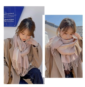 Detail shot of a soft pink plaid cashmere-like scarf with fringe in a cafe setting