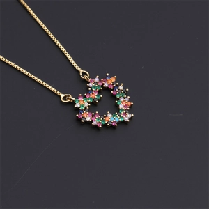 Macro shot of gold-plated heart pendant necklace with colorful zircon gemstones on black background