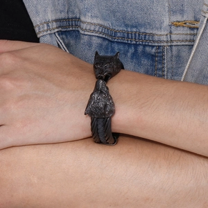 Detailed close-up of woven stainless steel men's bracelet with a double wolf head design