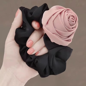 Satin fabric hair scrunchie with a 3D pink rose flower shown on a woman's wrist