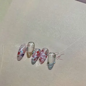 Close-up of Japanese style press-on nails featuring red floral art and gold accents