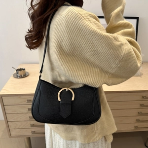Detail of black litchi grain shoulder bag with elegant gold horseshoe metal buckle