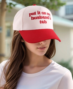 Detail of embroidered trucker hat with contrast brim and slogan on white crown
