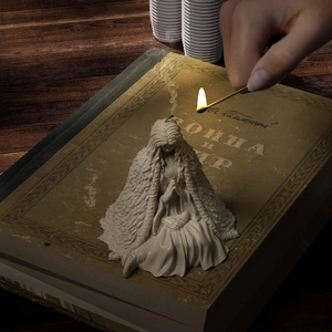 White kneeling angel prayer candle sculpture on a vintage book backdrop with flame
