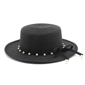 Close-up of black straw boater hat with pearl beads and velvet bow detailing