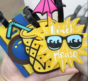 Close-up of flexible PVC luggage tags featuring cartoon sun, pineapple, and blue drink designs