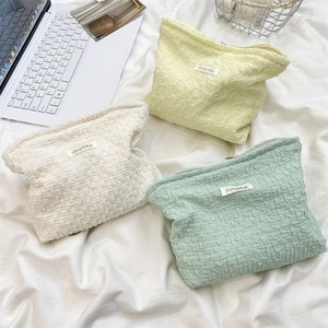 Detail of bubble textured makeup bags in pastel yellow, beige and mint green colors