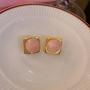 Dettaglio degli orecchini con pietra occhio di gatto rosa e cornice quadrata dorata
