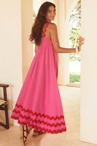 Close-up of pink long summer dress with red wavy scalloped edges and light cotton fabric