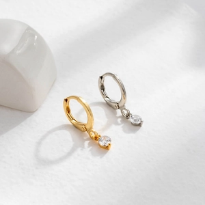 Fashion gold and silver cartridge earrings with clear round gemstone pendants on white