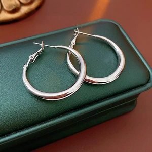 Detailed view of large silver hoop earrings on green leather jewelry storage case