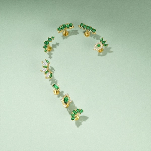 Set of 7 gold piercing studs with green zircons and floral hollow patterns on green texture