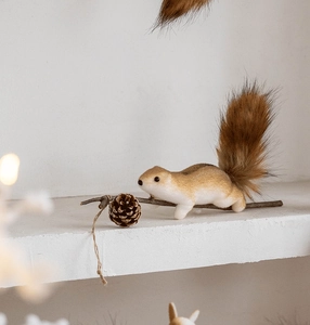 Close-up of a realistic squirrel ornament with faux fur texture on a wooden branch