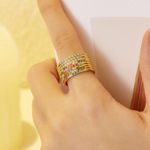 Set of seven slim gold rings with rainbow colored zircons on female fingers