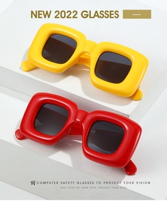 Detailed close-up of chunky Y2K square sunglasses in vibrant yellow and red frames