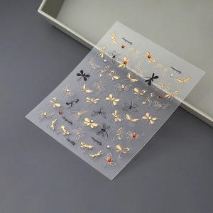 Detail of 3D dragonfly nail stickers with gold accents, black wings and red rhinestones
