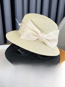 Detail of wide brim straw hats with large satin bows in beige and black colors