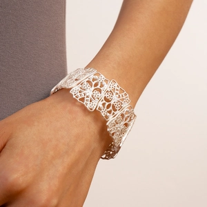 Detailed view of silver matte cuff bracelet with hollow floral textures on a wrist