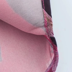 Vista macro delle cuciture e della trama stampata rosa-viola della camicia