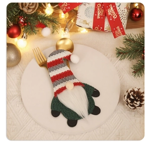 Close-up of a striped Christmas gnome cutlery holder on a plate with golden silverware