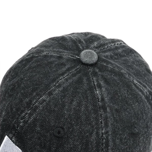 Détail du bouton cousu et des œillets d'aération sur une casquette de baseball délavée