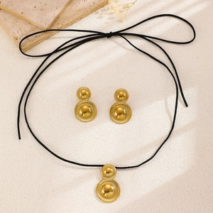 Detailed view of golden teardrop pendant necklace and earrings set on stone decor