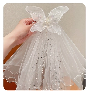 Close-up of white princess bow veil clip with faux pearls and sparkling sequins detail