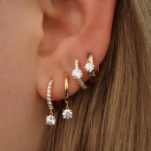 Close-up of four gold S925 silver hoop earrings with marquise diamonds on an ear