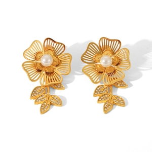 Close-up of 18K gold flower stud earrings with pearl center and rhinestone accents