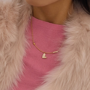 Detail einer goldenen Herzanhänger-Halskette mit Zirkonia-Pavé am Hals einer Frau